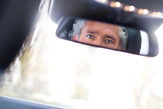 Die Augen eines Chauffeurs im Rückspiegel einer Limousine.