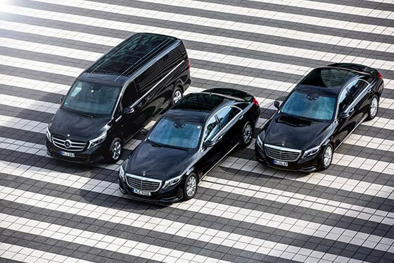 Zwei Limousinen und ein Minivan stehen in einer Reihe auf einem Parkplatz.